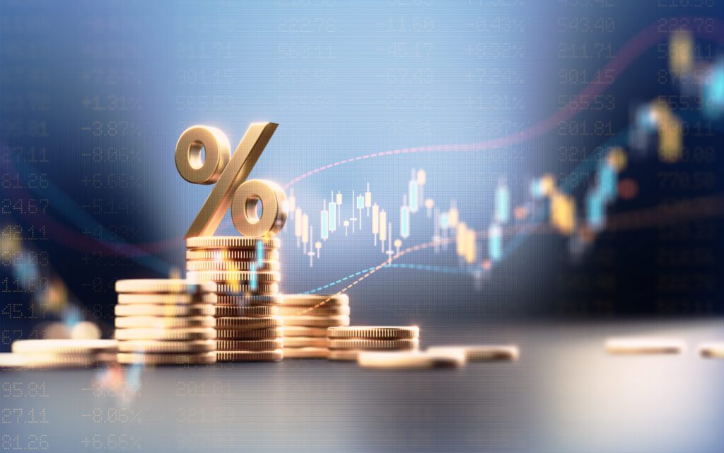 Golden percentage sign on stacked coins with stock market chart background.